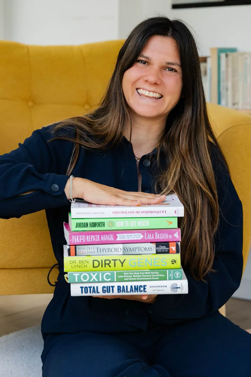 Mélanie Padovani, souriante, une pile de livres sur la santé intestinale dans les mains